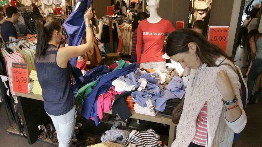 Varias chicas miran ropa en un comercio gallego.