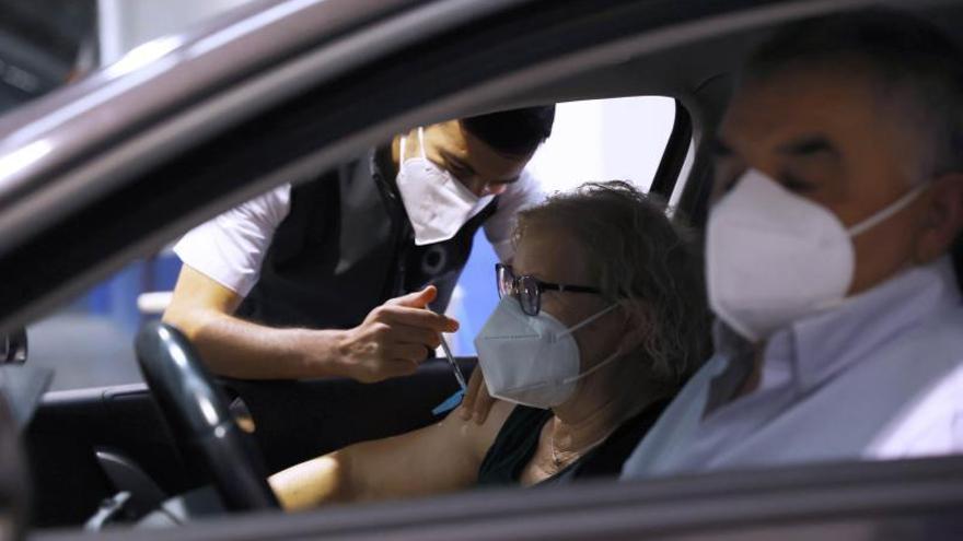Arriba, vacunación sin bajarse del coche en el Ifevi para personas de movilidad reducida. A la izq., puestos de vacunación en el pabellón contiguo para el resto de los citados. |   // ALBA VILLAR