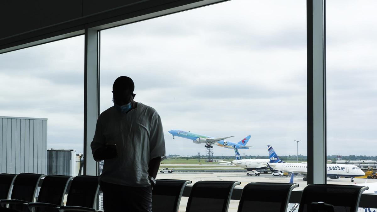 Un hombre espera en la terminal de salidas de un aeropuerto.