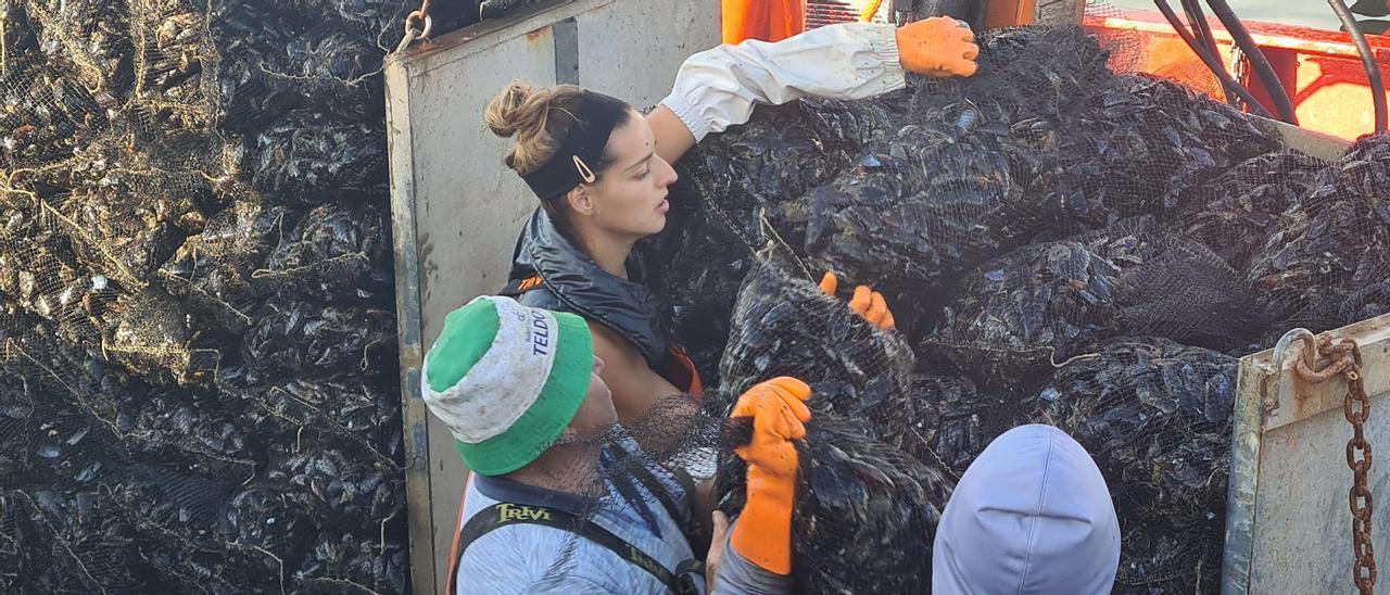 Una mujer descargando sacos de mejillón en el muelle.