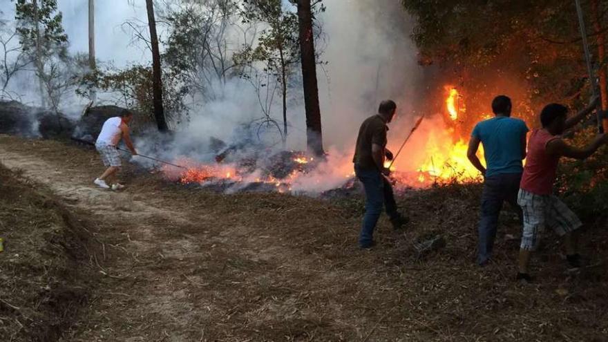 Vecinos de Ribadetea en una de las zonas en las que se logró extinguir las llamas, ayer por la tarde. // D. P.