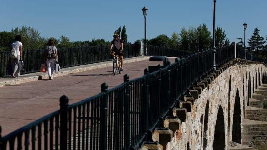 Ciclistas y peatones avanzan por el Puente de Piedra.