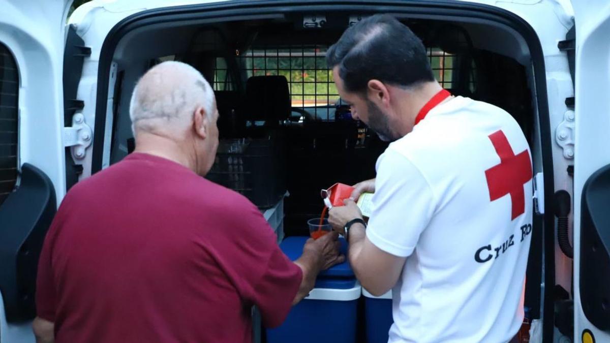 El voluntario José Antonio sirve gazpacho a una de las personas sin hogar en la zona de la Avenida Cádiz.