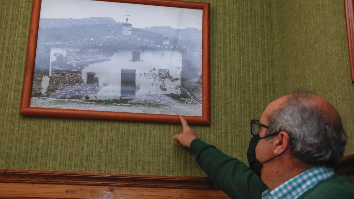 El alcalde de Cañaveral señala una fotografía de la antigua escuela de Villa del Arco, en su despacho