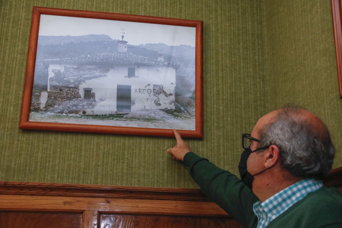 El alcalde de Cañaveral señala una fotografía de la antigua escuela de Villa del Arco, en su despacho
