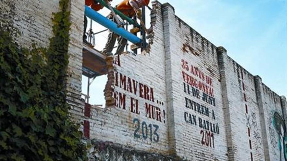 Dos operarios inician el derribo del muro de Can Batlló, abriendo el recinto al barrio, ayer por la mañana.