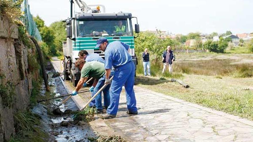 Empleados municipales limpian el vertido en la junquera del Lagares el pasado domingo.