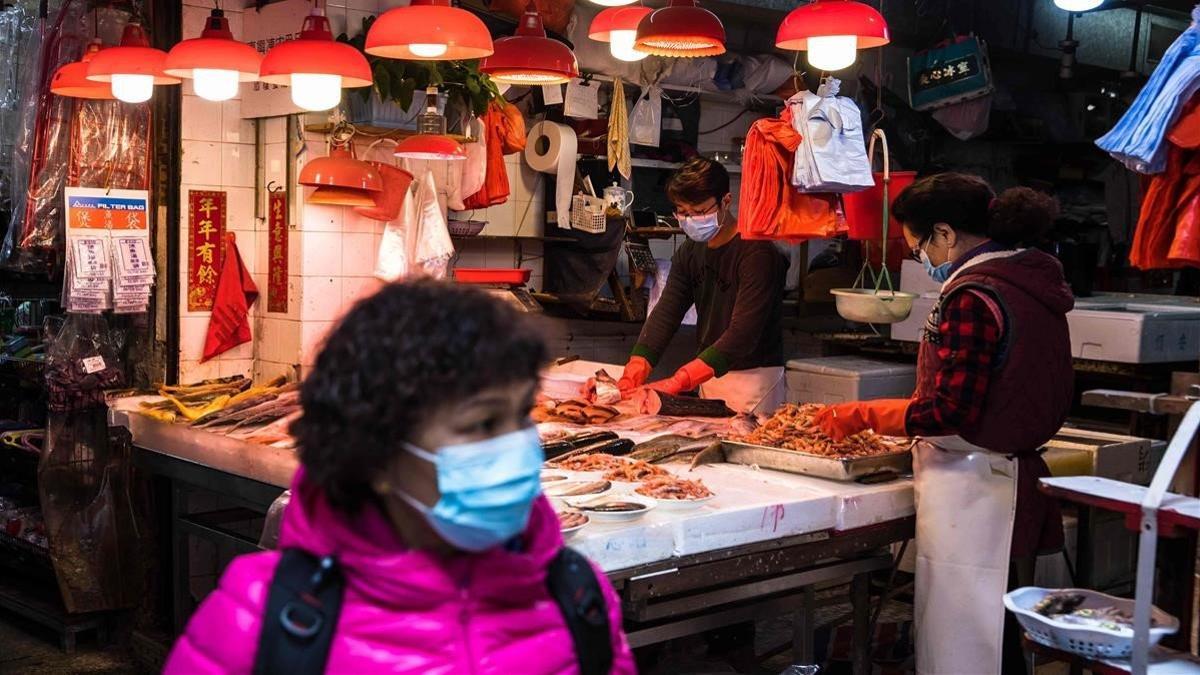 undefined52022335 a woman wearing a mask walks past a fish stall at a fresh fo200129194656