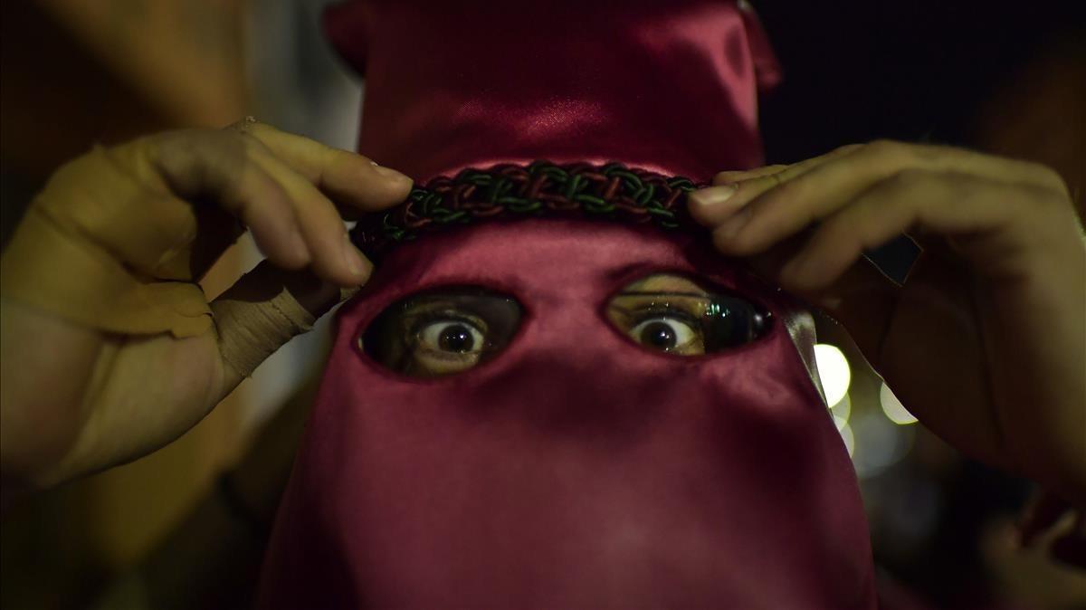 Un penitente se ajusta la vestimenta momentos antes de participar en la procesión de Calahorra.