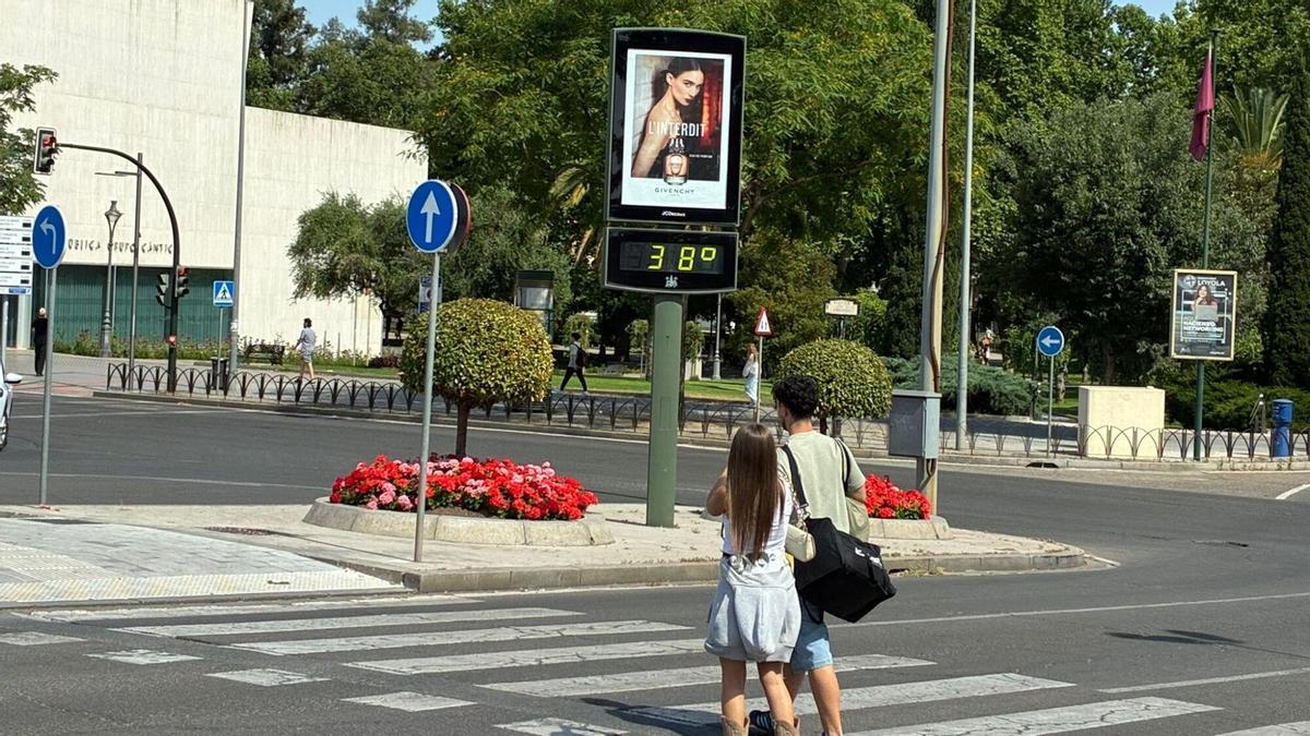 Un par de jóvenes caminan por un paso de peatones cerca de la biblioteca Grupo Cántico, en Córdoba.