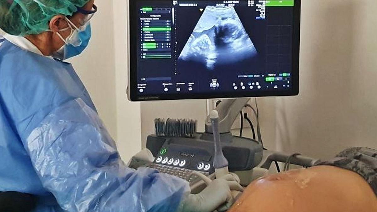 Una profesional sanitaria realiza en un hospital una ecografía a una mujer embarazada.