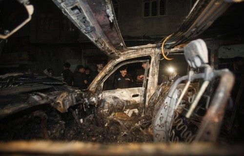 Oficiales recogen pruebas cerca de un vehículo dañado en un ataque suicida en Peshawar