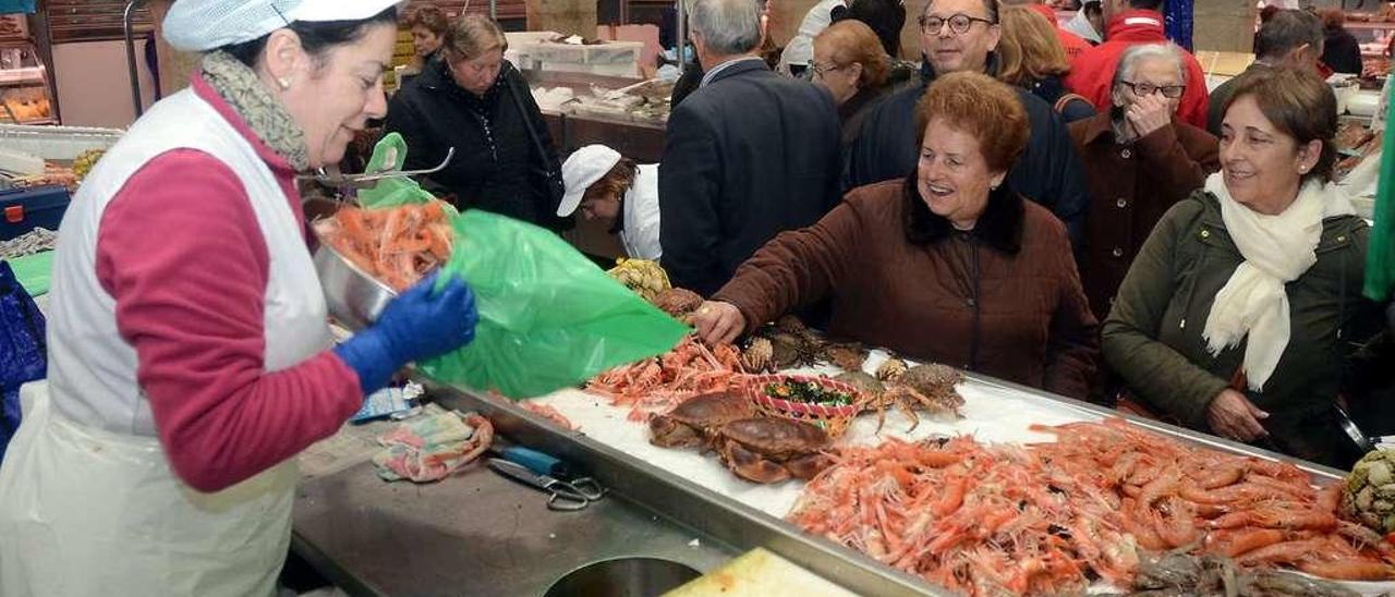 Una vendedora atiende a dos clientes en una de las bancadas de la plaza de abastos. // Rafa Vázquez