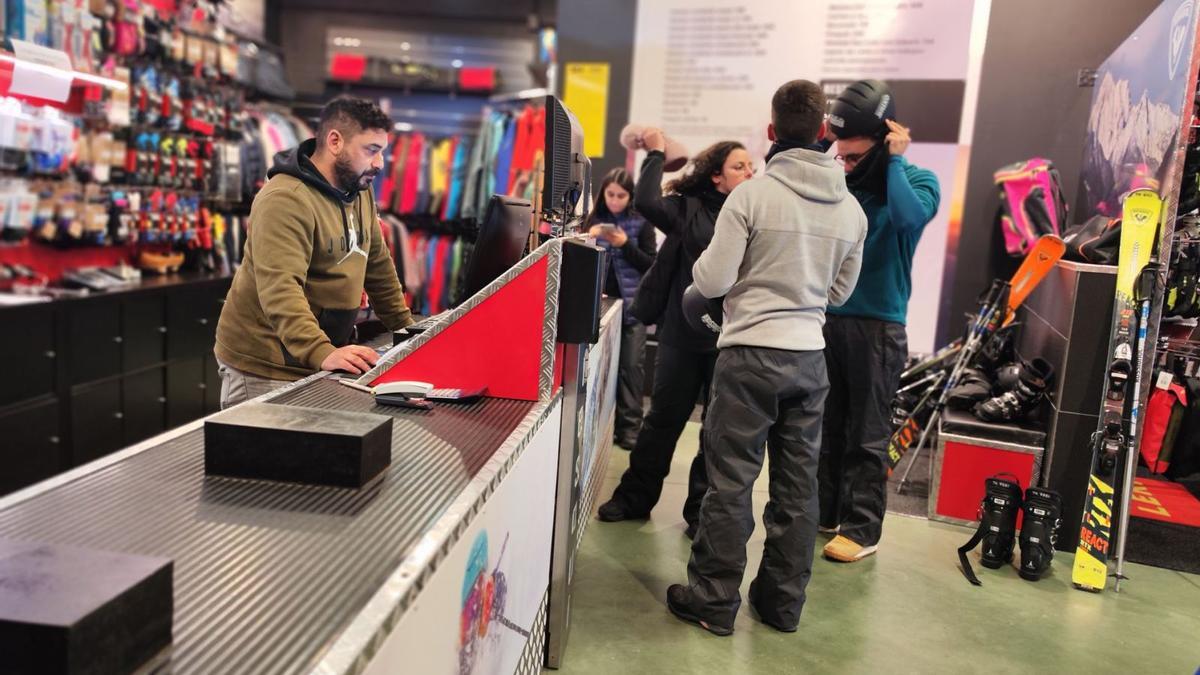 José Abel Martínez atiende a unos clientes portugueses que pasaron a alquilar equipos para acercarse a esquiar en los 100 metros de San Isidro. | A. Velasco