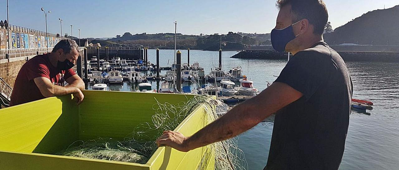 Ángel Gutiérrez, a la derecha, junto al buzo Jesús Gálvez, ayer, en el puerto de Candás, preparando las redes de su lancha.