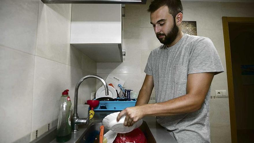 Marc Bauzá, un estudiante de 21 años, limpia los platos en el piso que le ha cedido su madre.