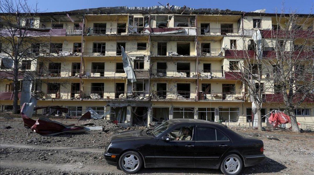 undefined55818442 file photo  a man drives a car past a damaged building follo201110000642