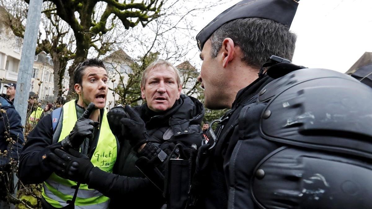 Varios  chalecos amarillos  forcejean con gendarmes galos mientras aguardan la llegada del presidente frances  Emmanuel Macron  a un debate con alcaldes de una zona rural del sur este viernes en Souillac