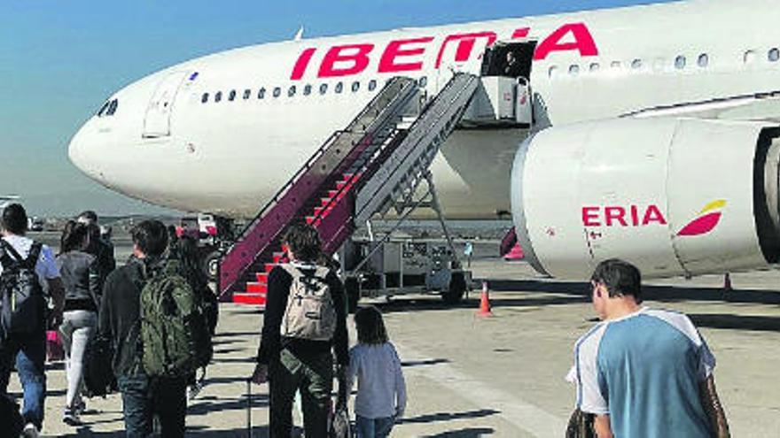 Pasajeros se dirigen a un avión de Iberia para embarcar.