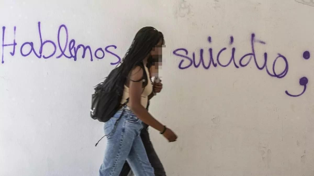 Una joven frente a una pintada sobre la prevención del suicidio. Una joven frente a una pintada sobre la prevención del suicidio.
