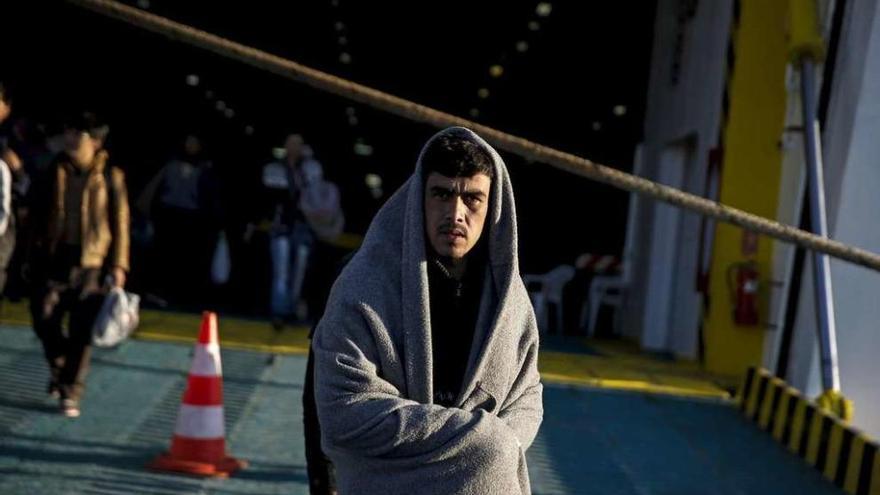 Un refugiado sirio, cubierto con una manta, llega al puerto del Pireo en el ferry de Lesbos. // Reuters