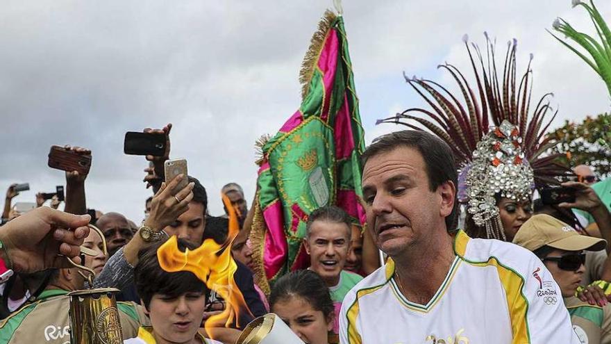 El alcalde de Río de Janeiro, Eduardo Paes, sostiene la antorcha olímpica.