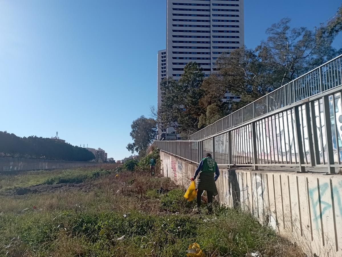 Trabajo de limpieza en el río con uno de los rascacielos de Martiricos al fondo.