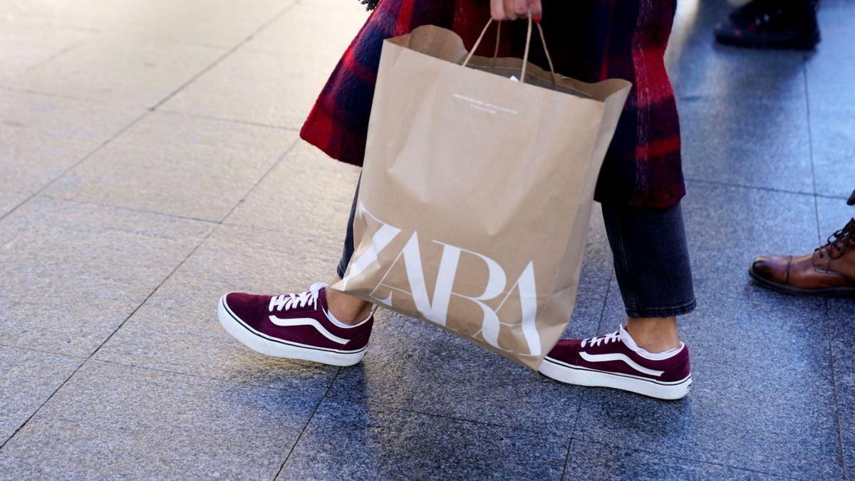 Una compradora passeja pel carrer amb una bossa de Zara. | REUTERS