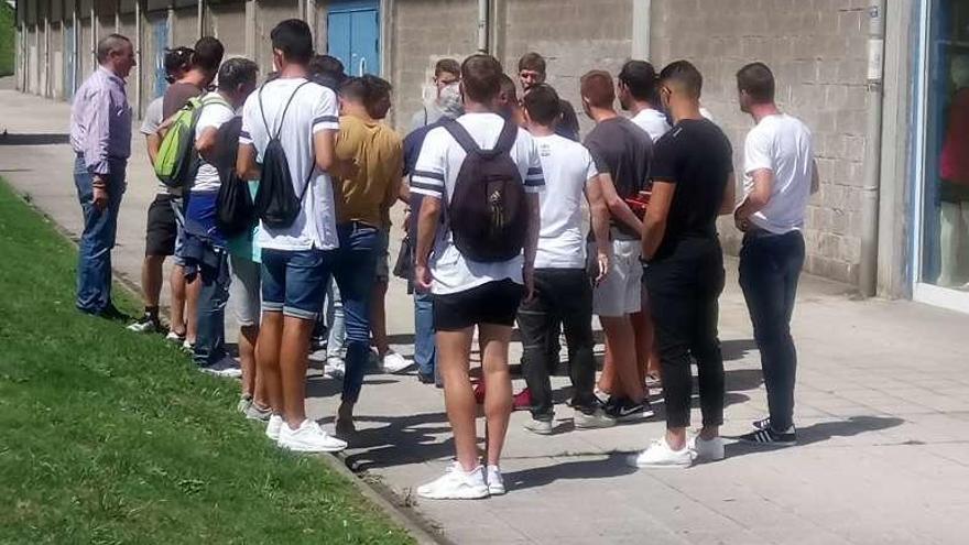 Jugadores, técnicos y directivos de Real Avilés GD conversan a las puertas de la tienda oficial tras no poder acceder al campo.