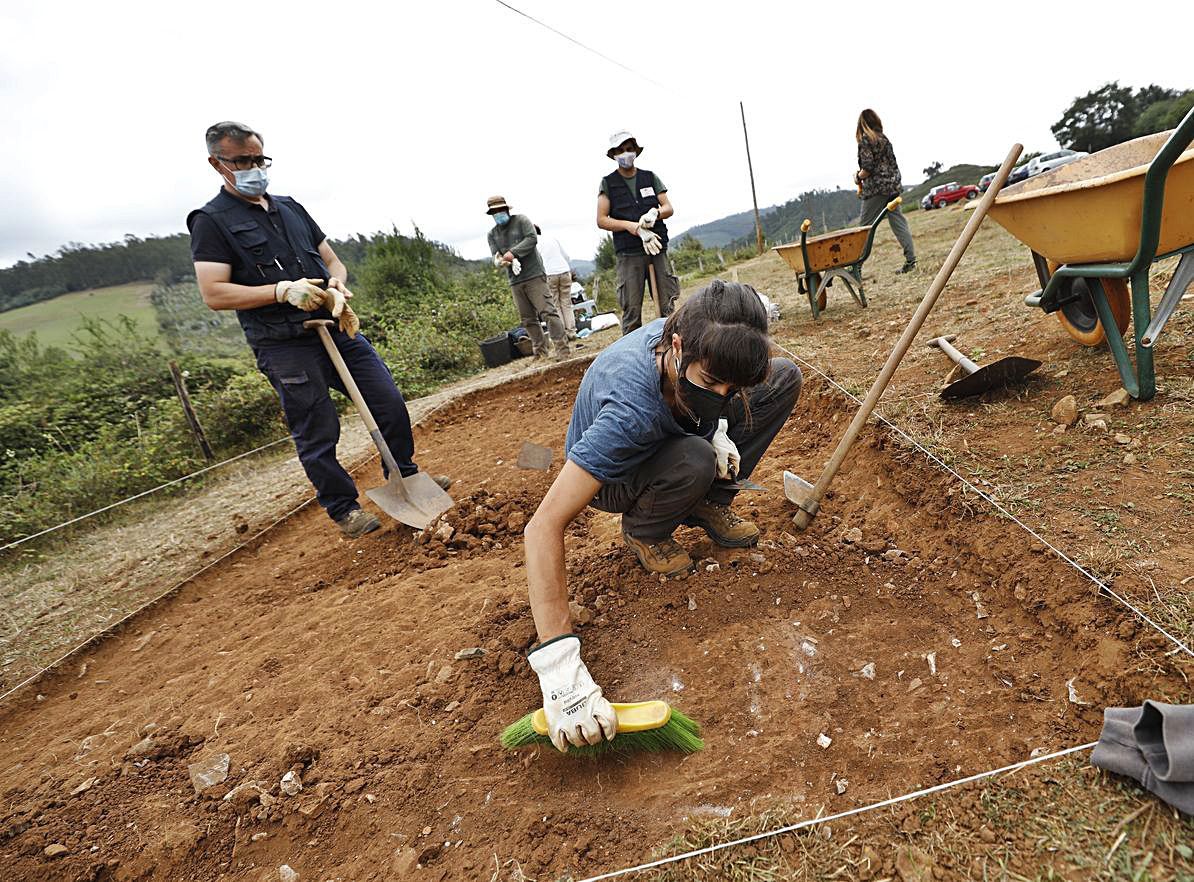 Los arqueólogos Alejandro Sánchez e Irene Faza; y al fondo, los arqueólogos Valentín Álvarez y Adrián Piñán y la restauradora Paula Ablanedo, ayer, iniciando la excavación en La Estaca. | L. Murias