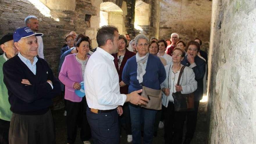 El alcalde de Villanueva de Oscos, José Antonio González Braña (en el centro), ayer, ejerciendo de guía por las ruinas del monasterio de Santa María para un grupo de mayores participantes en el encuentro.