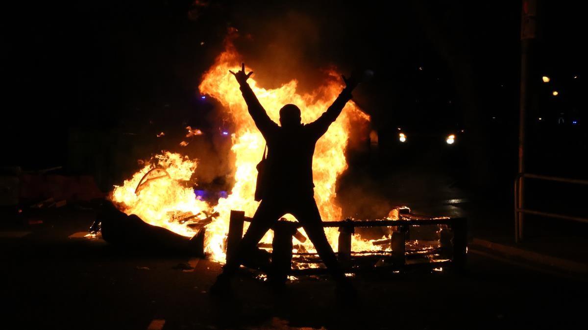 Un manifestante en el centro de Barcelona, frente a un contenedor ardiendo, el miércoles.      