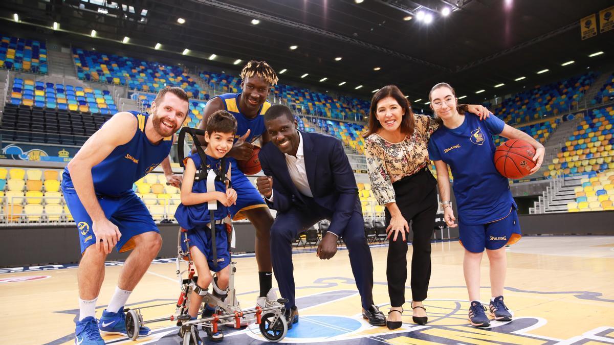 Los jugadores del Granca John Shurna y Khalifa Diop, junto a su presidente Sitapha Savané, posan junto a dos deportistas de su 'Proyecto Suma' y a Beatriz Mato