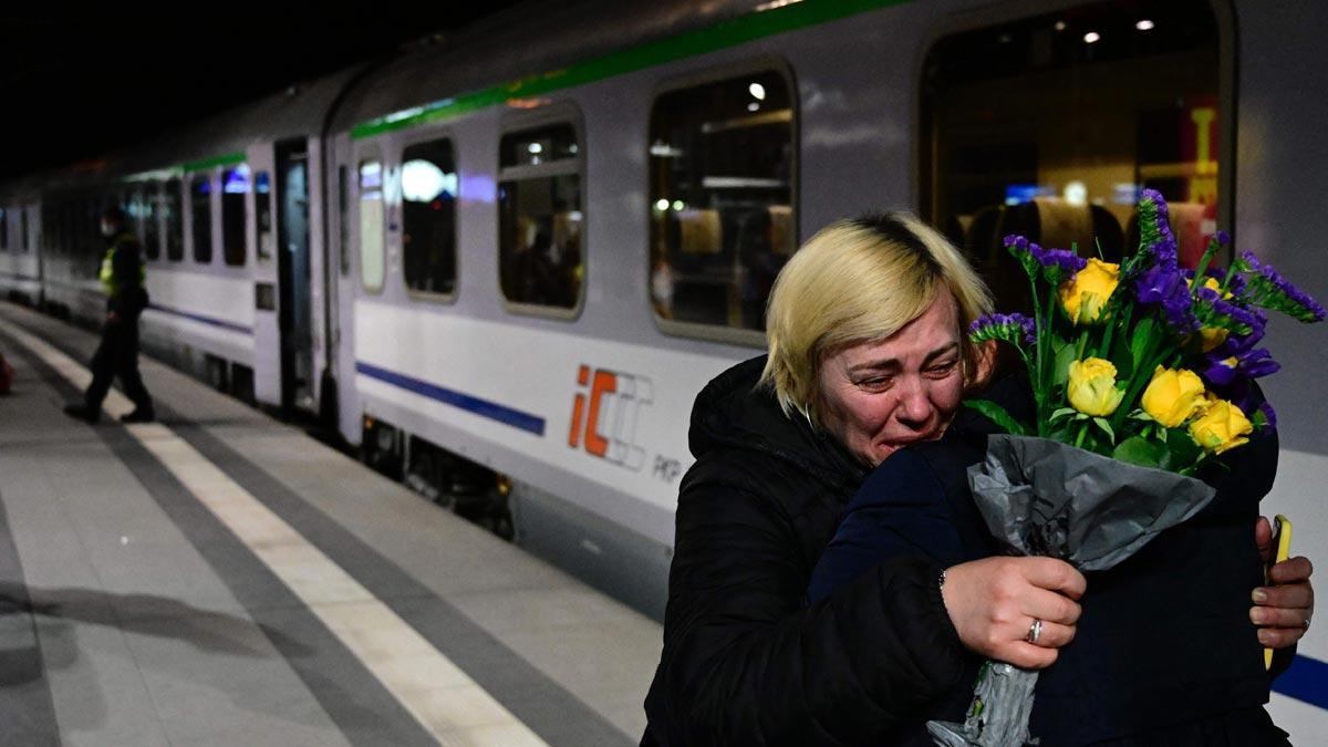 Una mujer es recibida con flores y consolada por un amigo tras llegar desde la frontera de Ucrania hasta la estación central de Berlín.