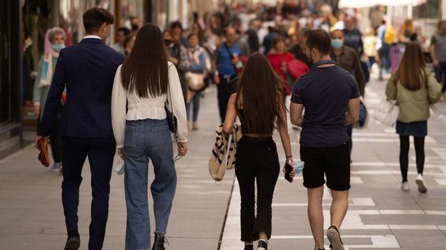 Varios jóvenes caminan en grupo por la calle de Santa Clara.
