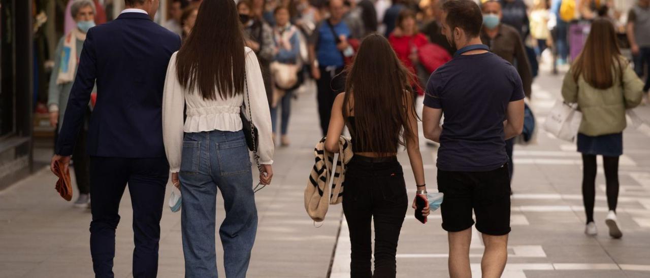 Varios jóvenes caminan en grupo por la calle de Santa Clara.