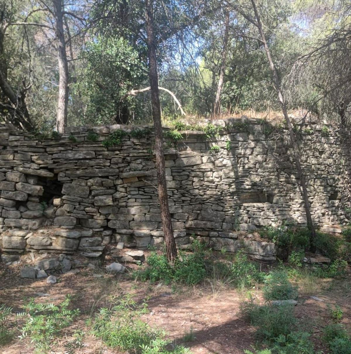 El recinte fortificat té planta en forma de L delimitat per murs de pedra seca