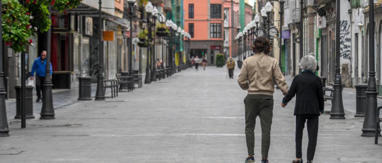 Una persona ayuda a una anciana en la calle Mayor de Triana.