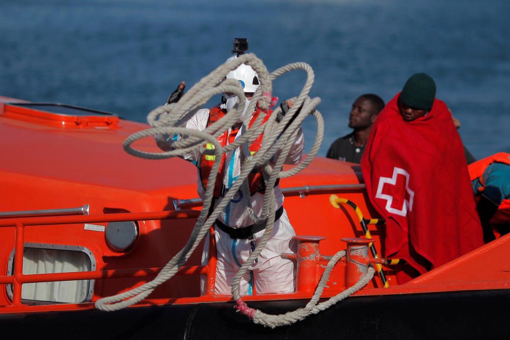 Migrants stand on a rescue boat upon arriving at ...