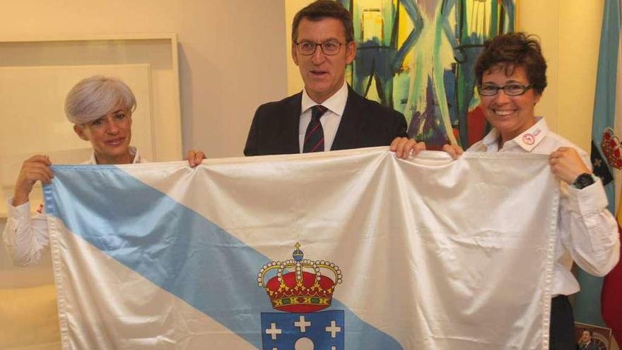 El presidente de la Xunta, Alberto Núñez Feijóo, entregando la bandera a las dos gallegas. // Conchi Paz