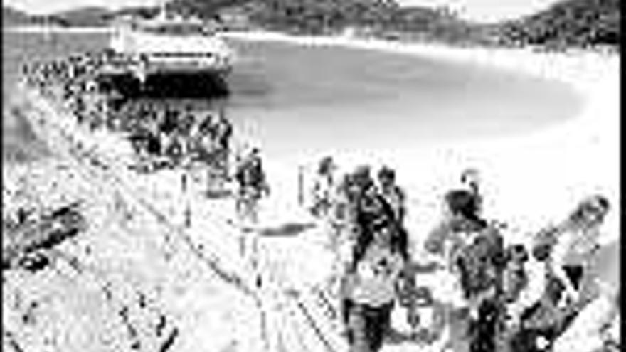 Turistas desembarcan en el muelle de la playa de Rodas, elogiada por la prensa británica.