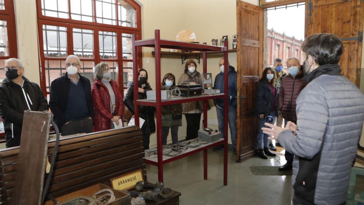 Sergio Delgado, a la derecha, dando explicaciones a los visitantes en la antigua fragua. A la derecha, los asistentes, en la planoteca de Hunosa. | Fernando Rodríguez