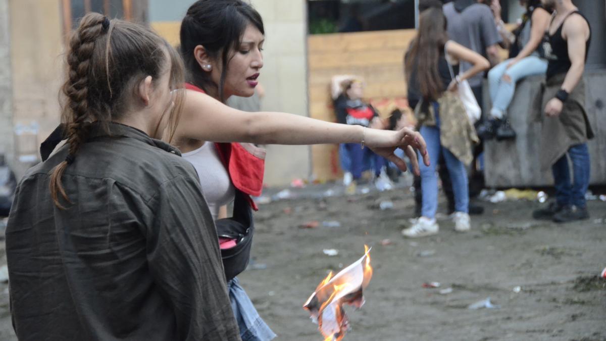 Una noia crema una carta al centre de la plaça