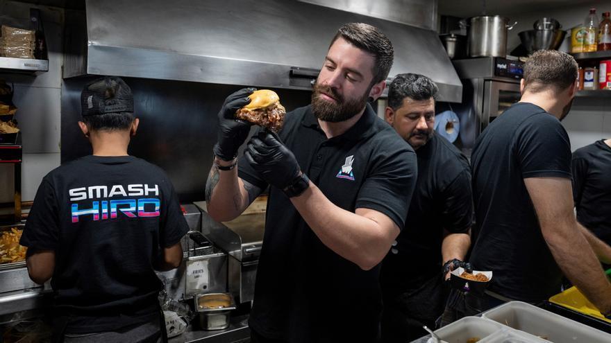 Esttik, en la cocina con el resto del equipo de Smash Hiro, muestra una de sus &#039;smash burgers&#039; recién hecha.