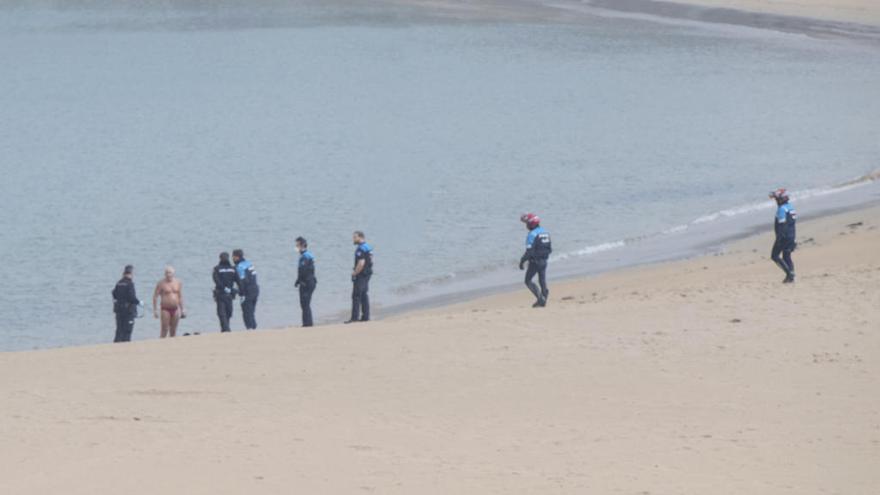 Efectivos policiales, esta mañana, en la playa de Poniente, ante el gijonés infractor, en bañador