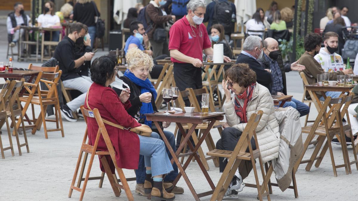 Varias personas disfrutan de una terraza en Gijón.