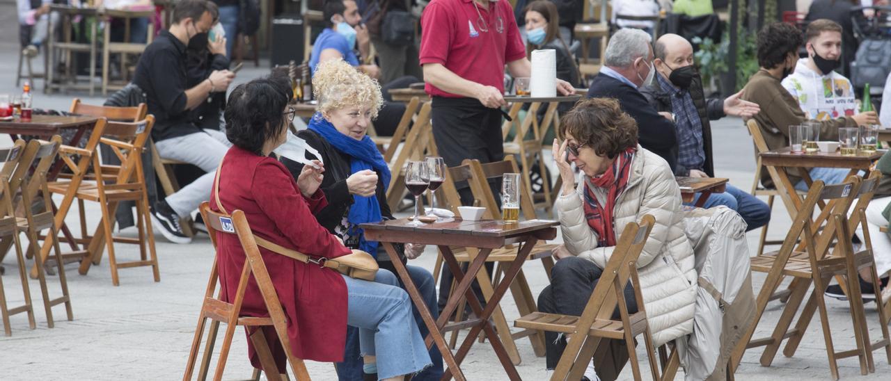 Varias personas disfrutan de una terraza en Gijón.