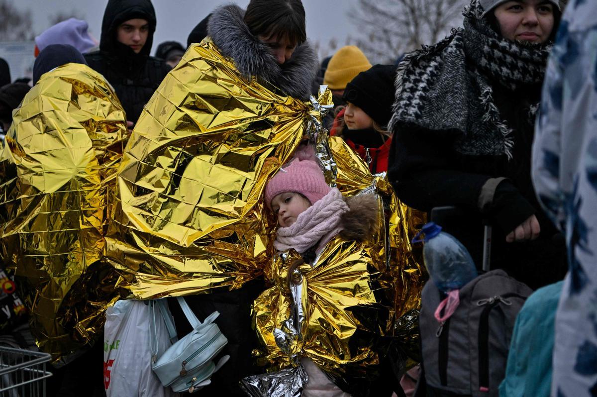 La gente espera en temperaturas heladas para ser trasladada a una estación de tren, después de cruzar la frontera de Ucrania con Polonia, en el cruce fronterizo de Medyka en Polonia, el 7 de marzo de 2022.