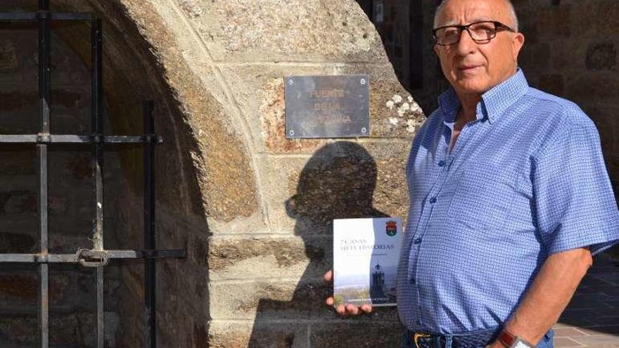 Faustino Gallego muesta su libro ante una fuente tradicional.