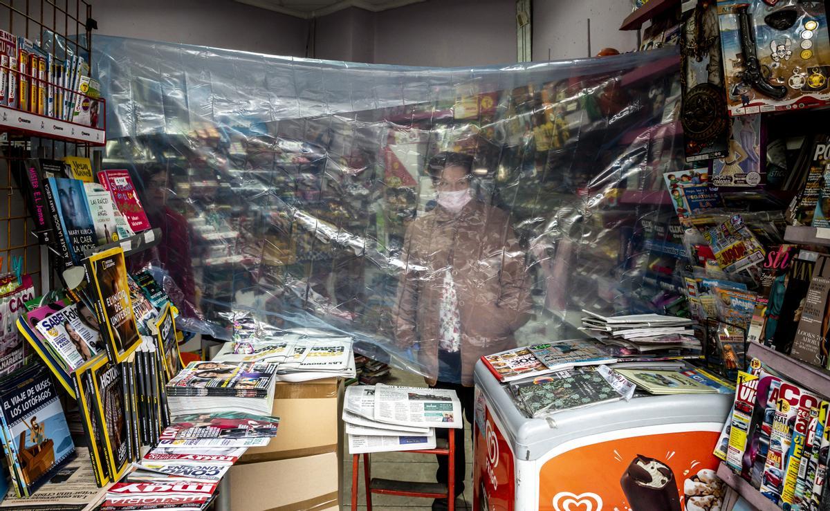 Una kiosquera se protege con un plástico en el primer día laborable tras decretarse el confinamiento el 14 de marzo de 2020.